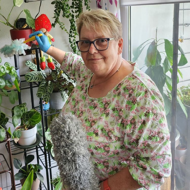 Mitarbeiterin mit Staubwedel in der Wohnung eines Klienten 