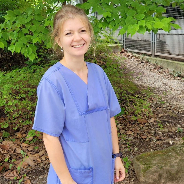 Nora, Mitarbeiterin der Mobilen Pflege, im blauen Kasack vor den Büroräumen.